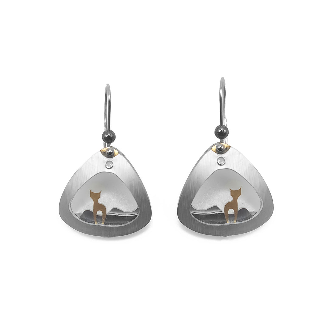 Rounded, triangular silver-coloured frame with gold-coloured cat standing inside. Grey and silver-coloured hills in background. Brushed and anodized aluminum. Minimalist design.