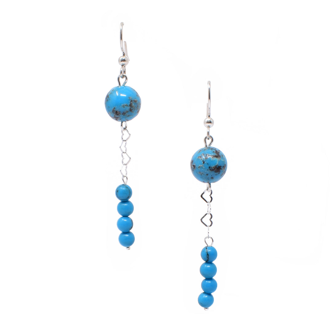 For both earrings, round bead of turquoise at top. Below, silver hearts interlock, leading down to four stacked smaller round turquoise beads. Metal is sterling silver.