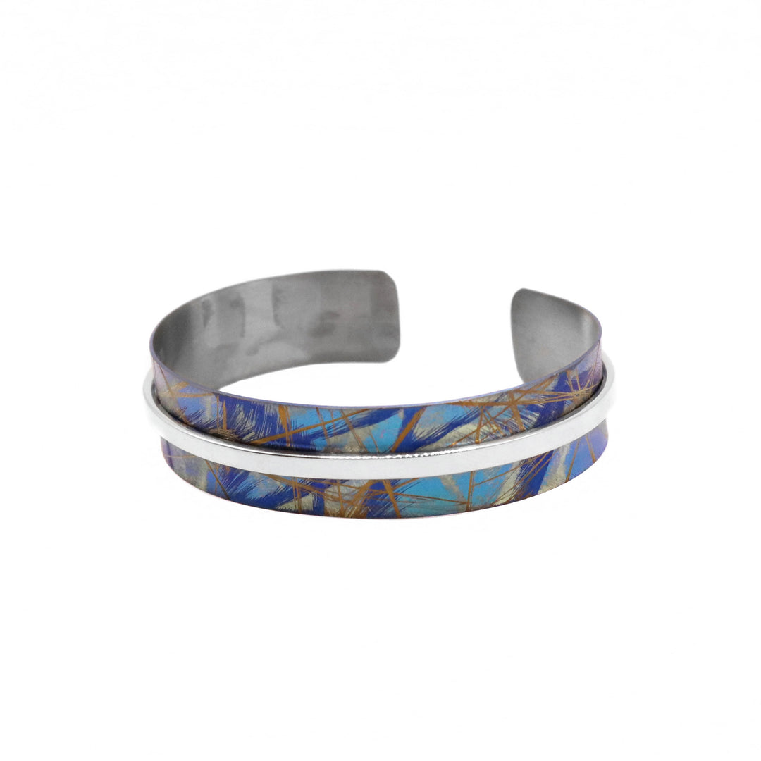 This titanium bracelet cuff has been made using sterling silver and anodized titanium. There is a single titanium band with a gap in the back and a thin silver wire running through the cenetr of the band. There are brilliant colored (gold, turquoise, purlpe) designs on the surface of the titanium that have been achieved by anodizing the metal.
