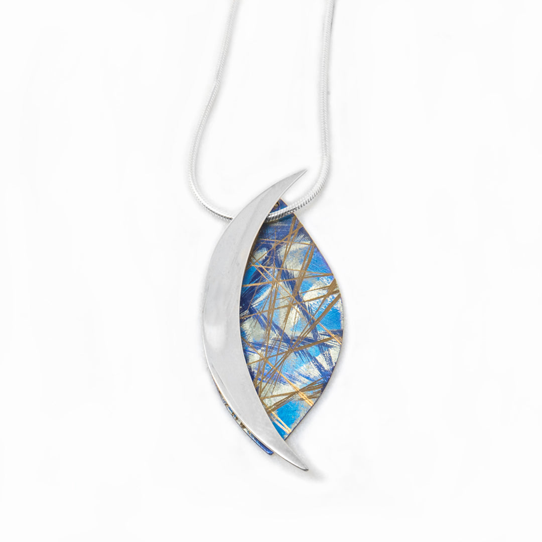 This unique titanium necklace pendant is made from anodized titanium and sterling silver. There is a large, vertical oval part made from the titanium and is blue with multi colored designs on the surface of it. There is a dainty, crescent shaped piece on the side of the piece made from brilliant sterling silver.