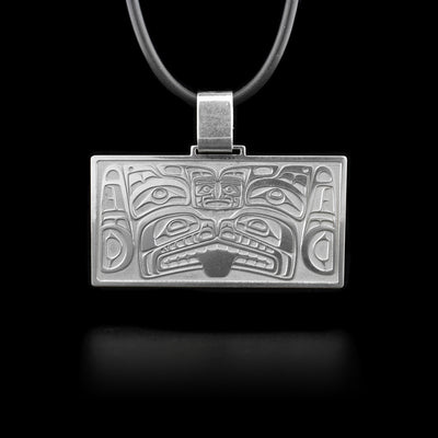 This sterling silver pendant is shaped like a wide rectangle and has a thick bail.  Carved into the pendant are depictions of the Orca and the Frog.