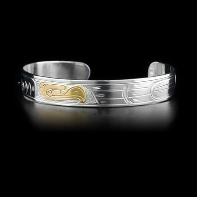 This sterling silver cuff bracelet has a thin band with a depiction of the Eagle carved into it. The head of the eagle is made from 14K gold.