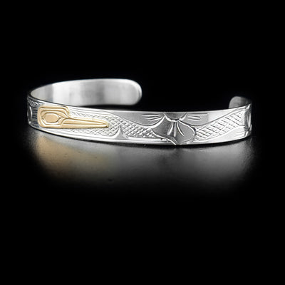 This small cuff bracelet has a thin, sterling silver band with a depiction of the Hummingbird and a flower carved into it. The head of the Hummingbird is made from 14K gold. 