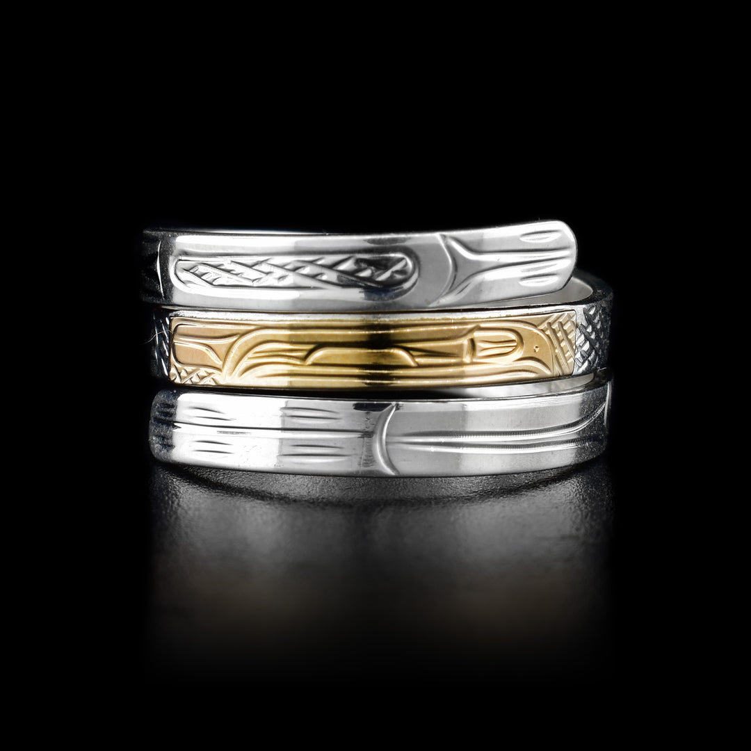 This sterling silver wrap around ring has three bands across the top of it. The top of the middle band is made from 14K gold. There are three depictions of the Raven carved into the ring.