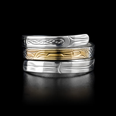 This sterling silver ring has three bands across the top of it. The top of the middle band is made from 14K gold. There are three depictions of the Raven carved into the ring.