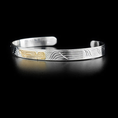 This sterling silver cuff bracelet has a thin band and carvings that depict the Wolf. The head of the Wolf is made from 14K gold.