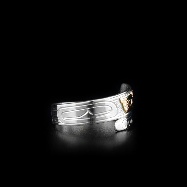This sterling silver and 14K gold ring has a band that wraps around the finger twice. There are carvings across the band and a depiction of the Owl carved into it. The face of the Owl is made from 14K gold.