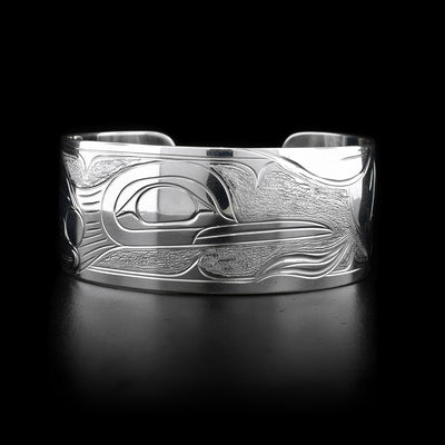 This sterling silver cuff bracelet is wide and has carvings that depict the Hummingbird and a flower on it.
