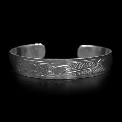 This Hummingbird bracelet has a single, sterling silver band with a gap in the back. There is a depiction of the Hummingbird carved across the surface of the band and a small Sun carved in the side of the band. The Hummingbird is depicted in a side profile and is facing the Sun. The head of the legend is in the center of the band and there are cross hatching designs in the negative space of the piece.