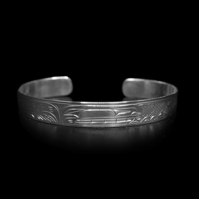 This dainty bracelet has a thin, sterling silver band with a gap in the back. The head of the Orca is carved in the center of the band and there are the backs of other whales with their dorsal fins breaching out of wave patterns. There are cross hatching patterns in the space behind the legends.