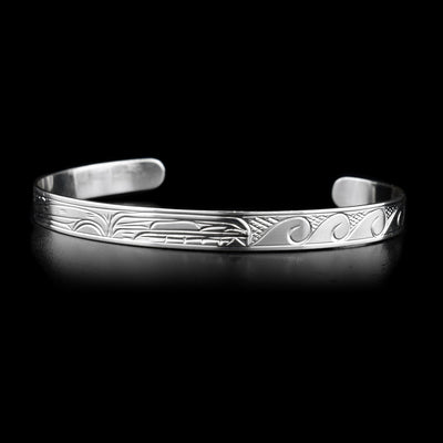 This sterling silver cuff bracelet is thin and has a depiction of the Orca on one end of the bracelet and wave patterns on the other.