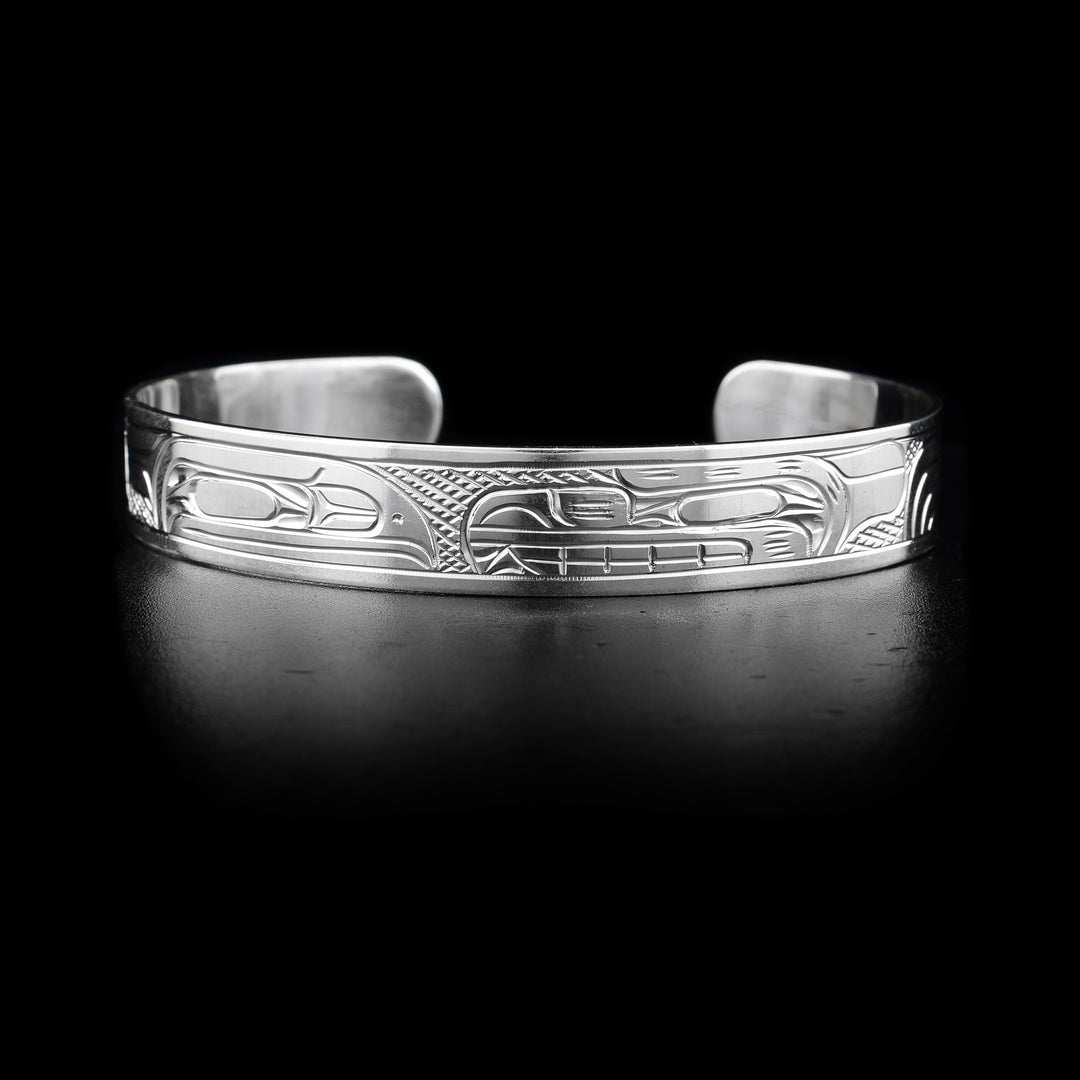 This sterling silver cuff bracelet has depictions of the Raven and the Bear carved into it. Their heads meet at the top of the bracelet.