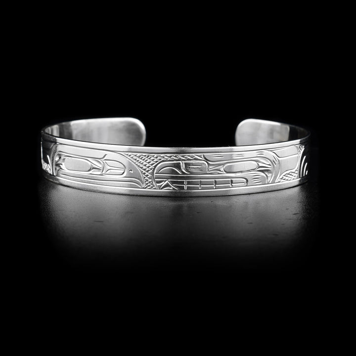 This sterling silver cuff bracelet has depictions of the Raven and the Bear carved into it. Their heads meet at the top of the bracelet.