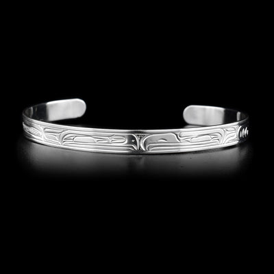 This sterling silver cuff bracelet is thin and has carvings that depict the Eagle and the Raven on it. Their heads meet at the top of the bracelet.