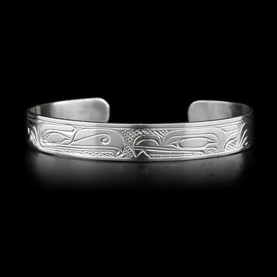 This sterling silver cuff bracelet is thin and has depictions of the Wolf and the Thunderbird carved into it. Their heads meet at the top of the bracelet. 