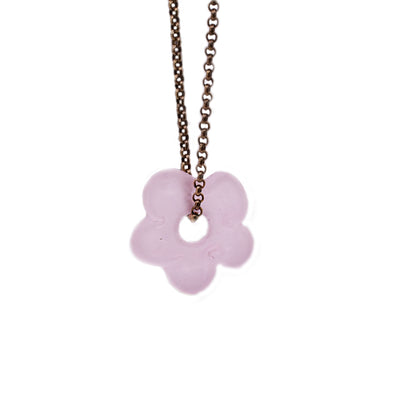 Thick, brass belcher chain with flat, light pink, matte glass flower pendant. Pendant has large, circular opening in center that chain goes through.