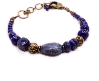 This clasp bracelet is made from copper and has various blue, lamp-worked glass beads on it.