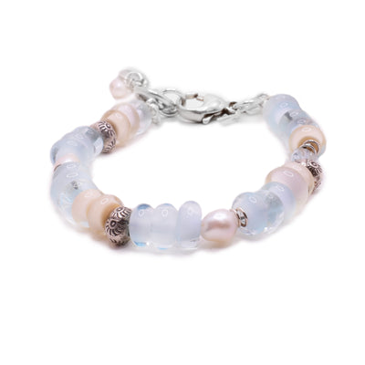 This sterling silver bracelet has blue and pink glass beads, with hand carved silver beads, and fresh water pearl.