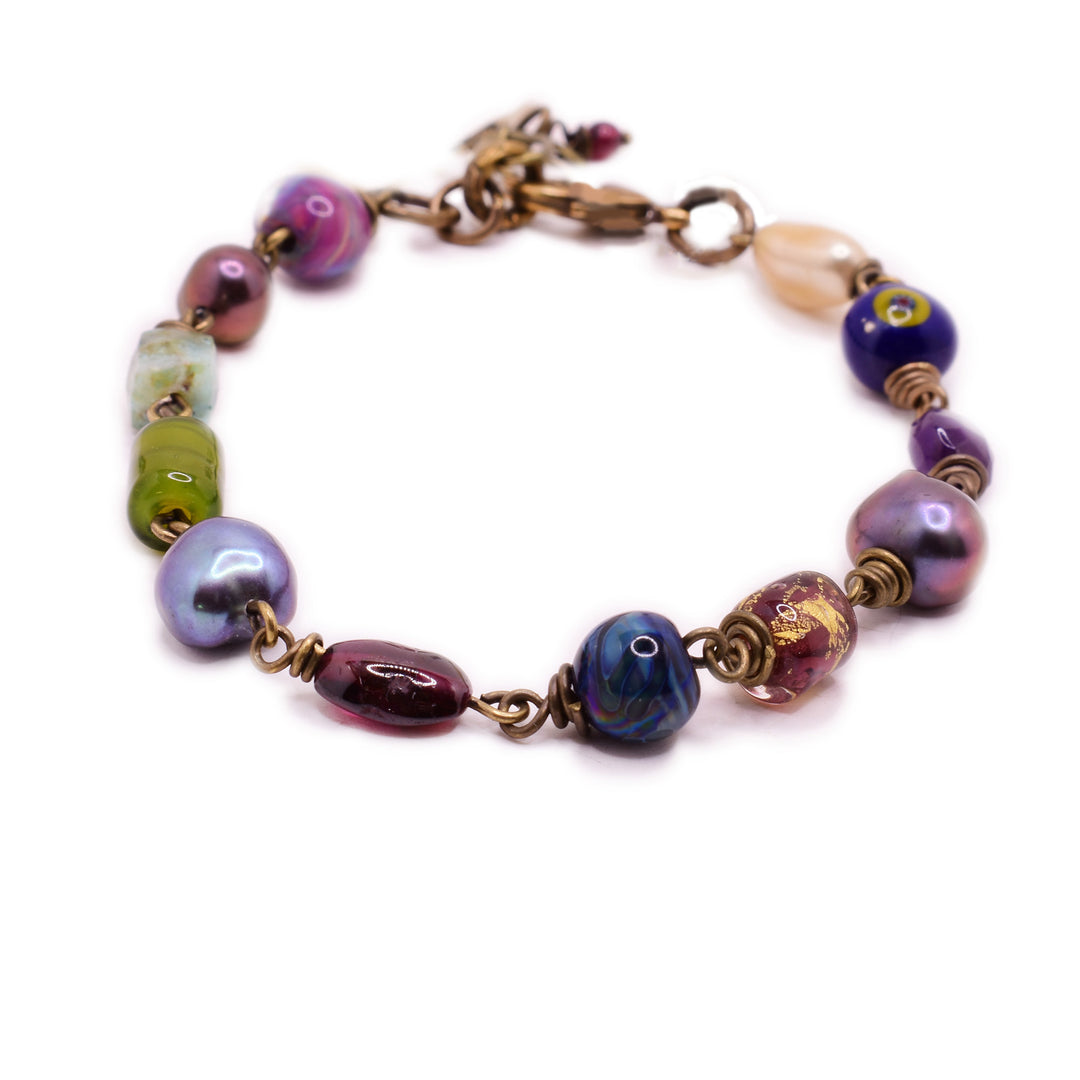 This unique brass bracelet has lampworked glass beads, freshwater pearls, and a ruby on it.