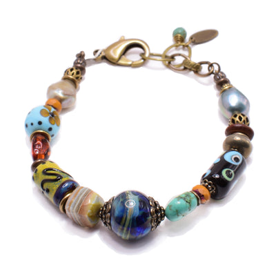 This unique glass bead bracelet features lamp wokred glass beads, pearls, rubies, turquoise and brass. The beads are all shaped, colored and designed uniquely.