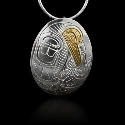 This sterling silver pendant is oval shaped and has carvings that depict the Hummingbird and a flower on it. The head of the Hummingbird is made from 14K gold.
