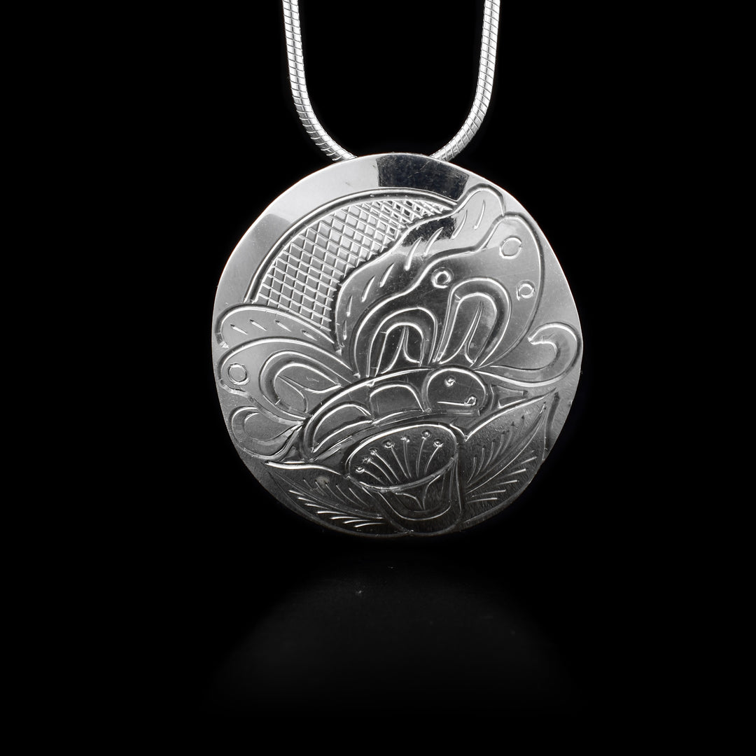 This sterling silver butterfly pendant has a circular shape and has a butterfly and flower carved into it