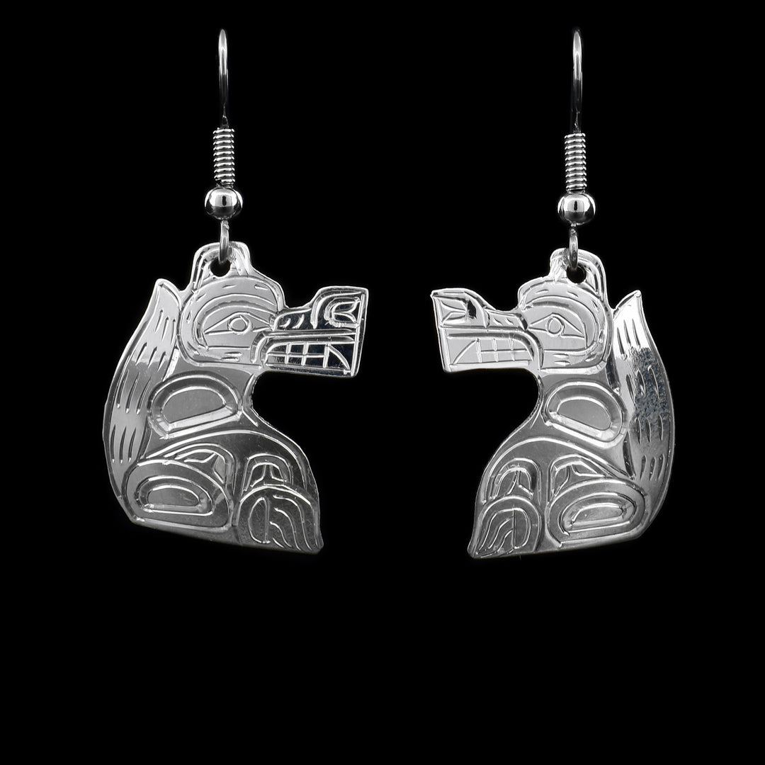 These sterling silver Wolf earrings have hooks that have Wolf shaped hangs attached to them. The Wolf has its face and body hand carved on it. The Wolf has a long snout and its tail goes up to the top of its head.