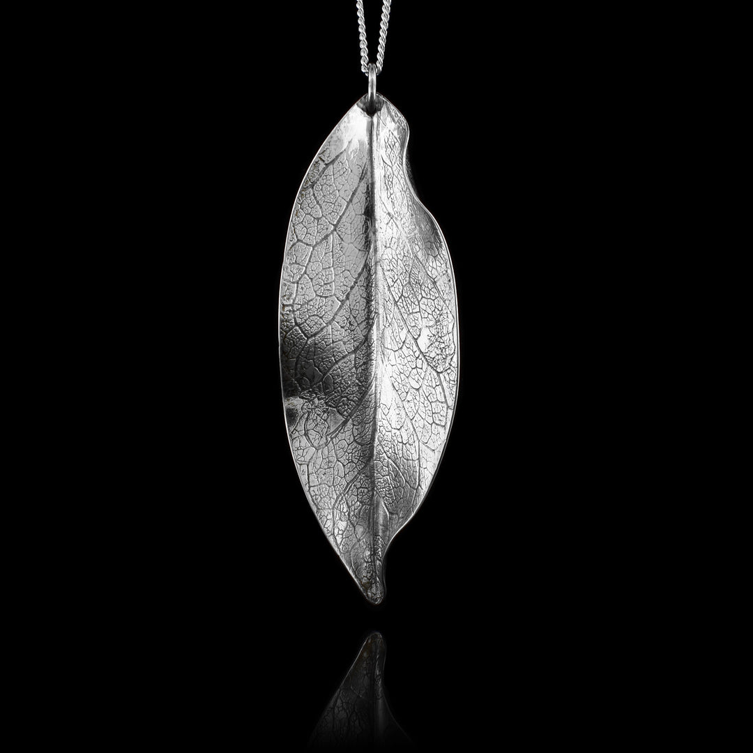 This leaf pendant necklace is made from sterling silver and has a dainty chain with a leaf shaped pendant. The pendant has folds and designs on the surface of it depicting a realistic leaf.