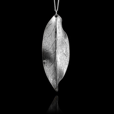 This leaf pendant necklace is made from sterling silver and has a dainty chain with a leaf shaped pendant. The pendant has folds and designs on the surface of it depicting a realistic leaf.