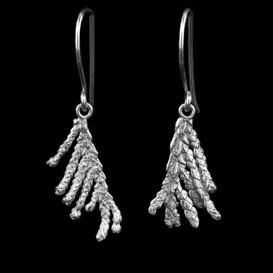These cedar tree earrings are made from sterling silver and have realistic hangs depicting cedar needle branches. The branches point down and dangle from the hooks.