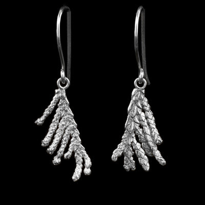 These cedar tree earrings are made from sterling silver and have realistic hangs depicting cedar needle branches. The branches point down and dangle from the hooks.