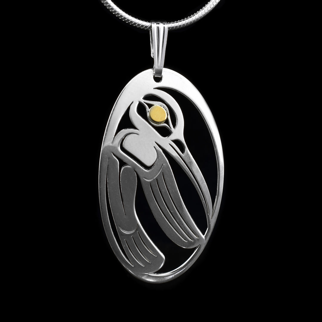 This hummingbird pendant is handcrafted. It features an elegant hummingbird design cut out from a polished sterling silver oval frame. With smooth, flowing lines that form the bird’s body, wings, and beak in a minimalist, stylized way. The hummingbird is shown in a side profile with wings folded down, mid-hover, and facing right. At the center of the design, a small round 14K gold accent represents the bird’s eye. 