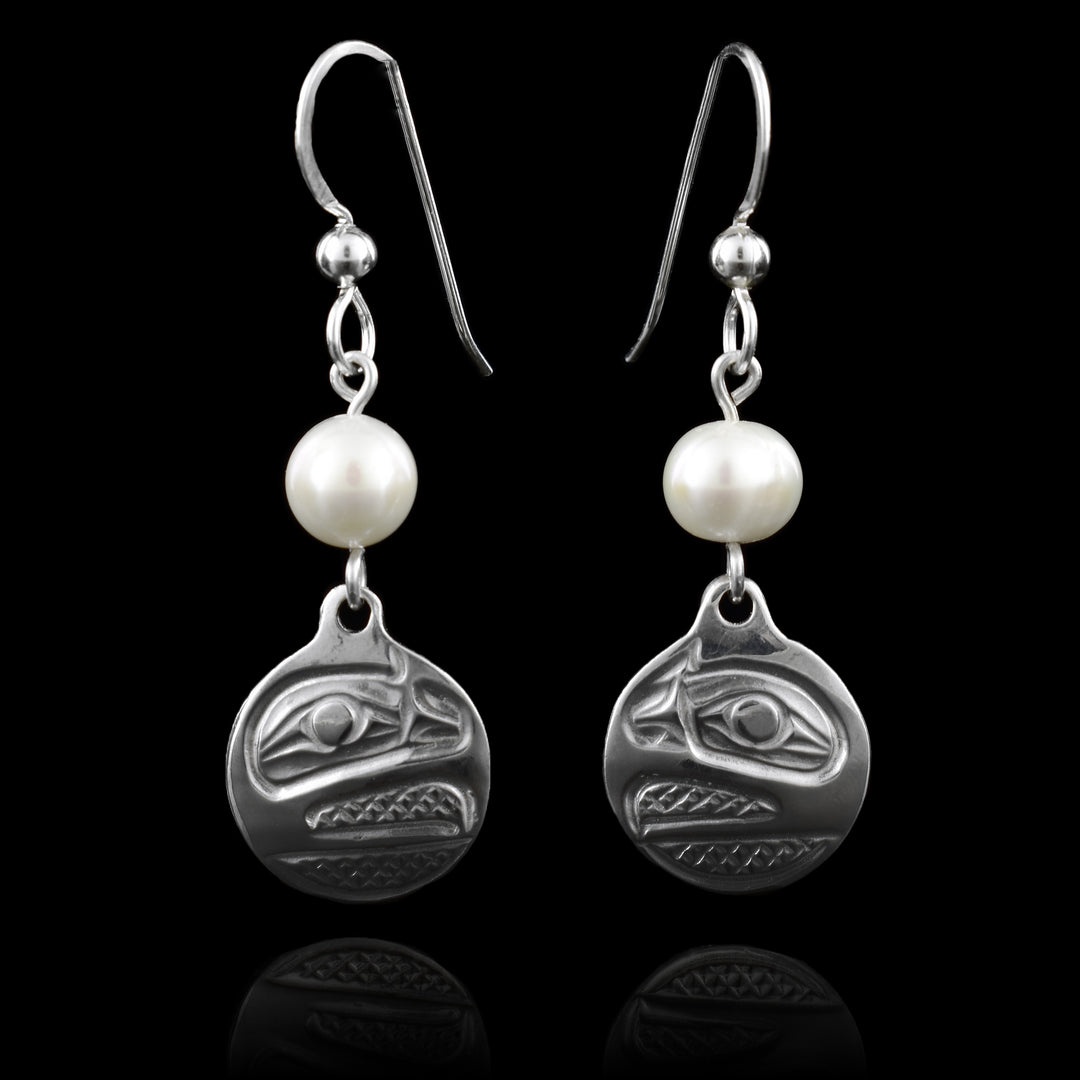 These elegant silver raven circular drop earrings showcase finely engraved Raven designs in sterling silver, symbolizing transformation and creativity. Each piece is accented with a classic freshwater pearl. Finished with classic French hooks.