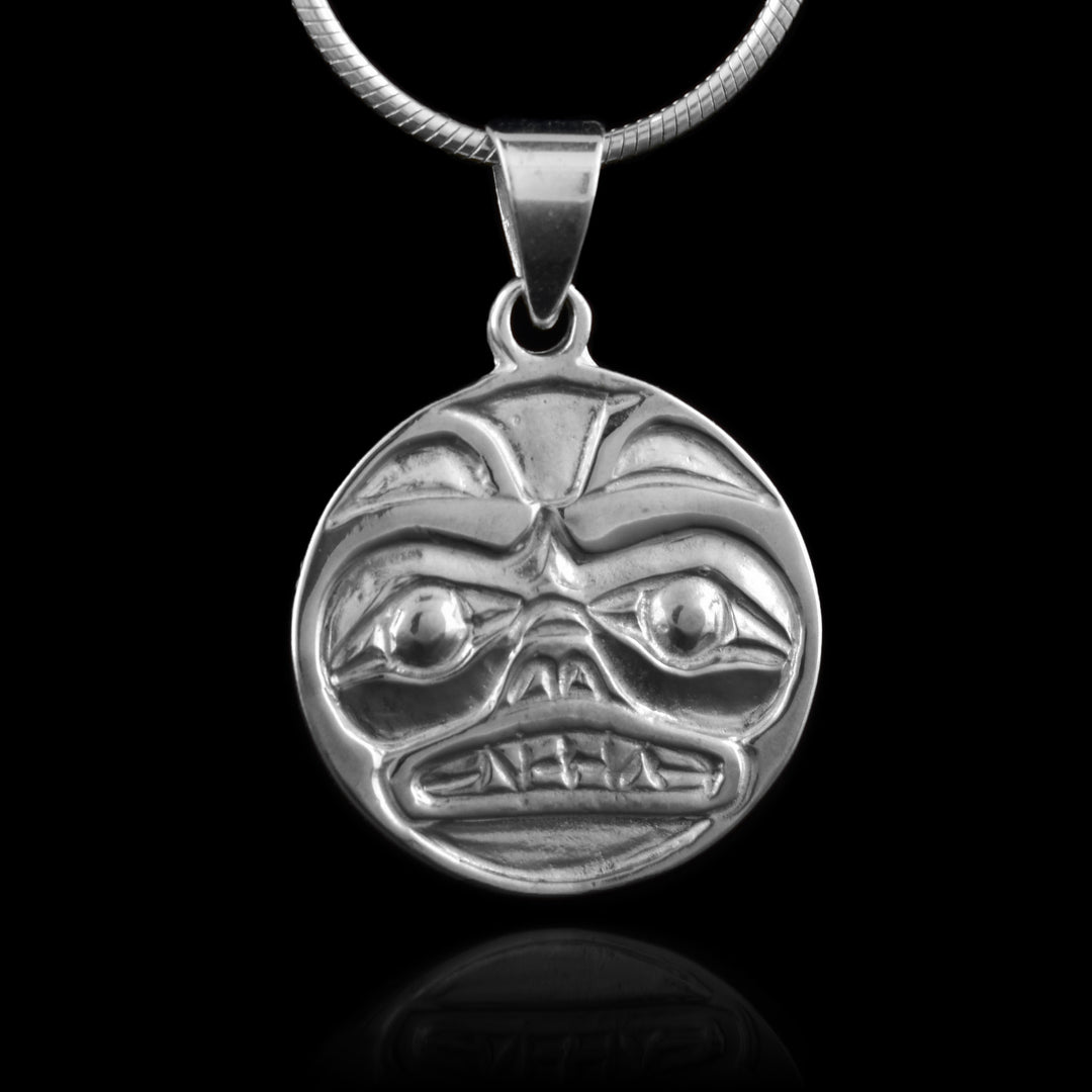 Sterling Silver Bear Cast Pendant by Carrie Matilpi. The design of the pendant is a bear looking forward. The bear has two small, pointy ears at the top; two large eyes staring forward; a short, stubby nose in the center of the pendant; and a set of pointy teeth underneath the nose.