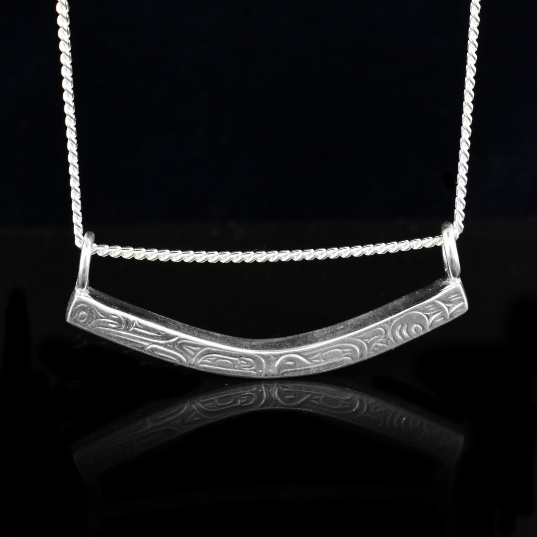 This sterling silver eagle orca bar necklace is a unique sterling silver bar and carved onto it is the legend of the eagle and orca. The bar is slightly curved and has to loops the the chain loops through.