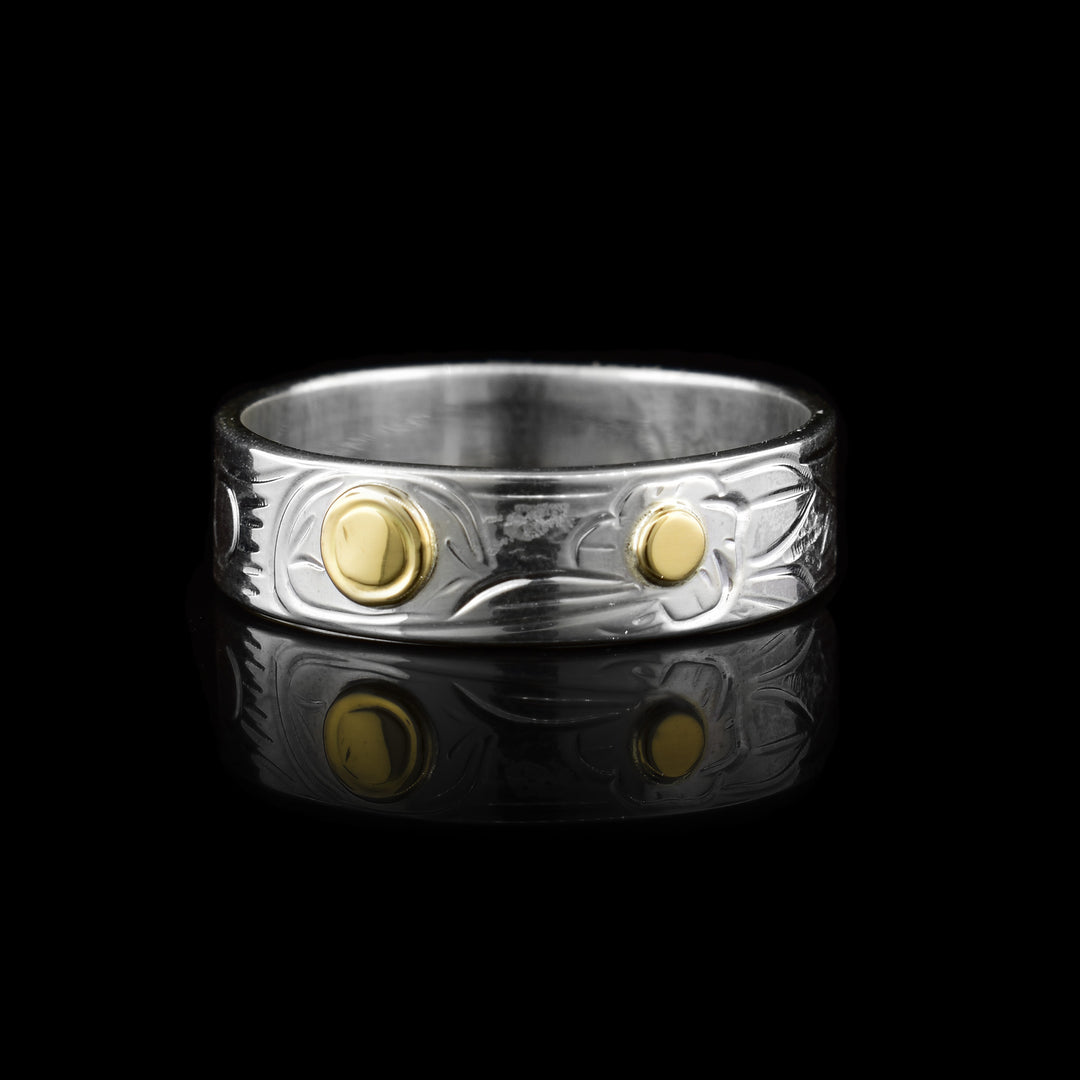 This thin sterling silver 14k gold hummingbird band ring. The majority of the ring is made out sterling silver with the legend of the hummingbird carved into it. For more detail the eye of the hummingbird and the middle of the flower are made with 14k gold.