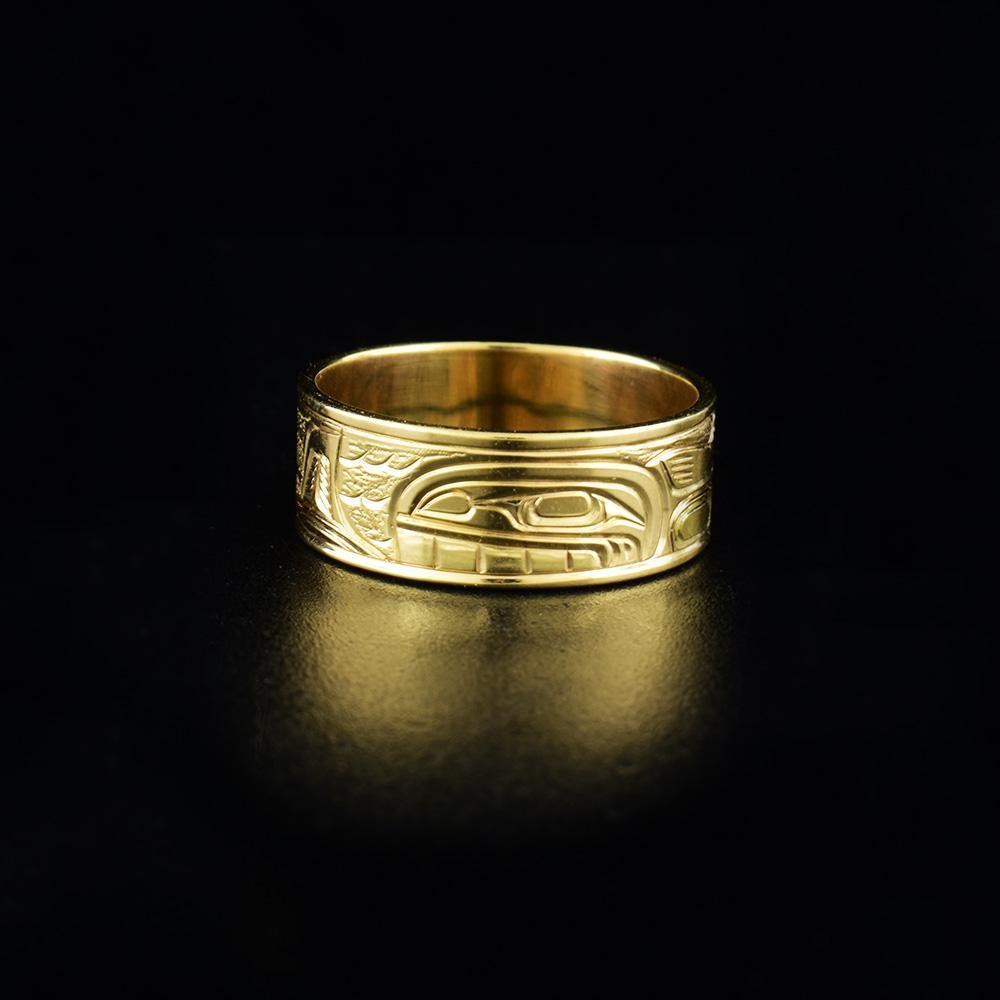 This 14k gold ring has a single wide band with a depiction of the Orca carved into the surface of the band.