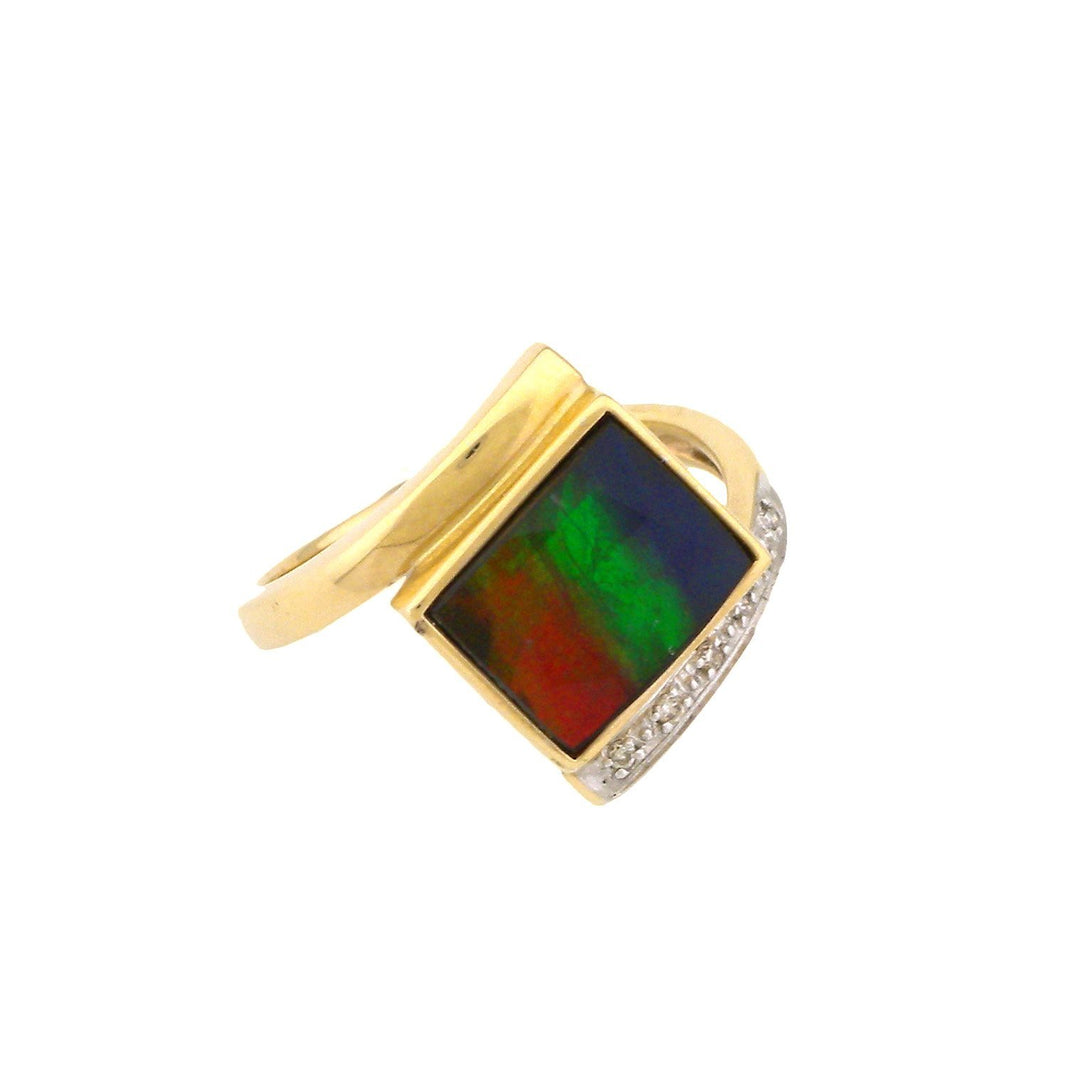 This unique ammolite ring is made from 14K gold, sterling silver, diamond and AA grade ammolite gemstone. The band is a gold rod that wraps around either side of the square shaped ammolite gem in the center. There is a silver embellishment on the band with a small diamond embedded into it.