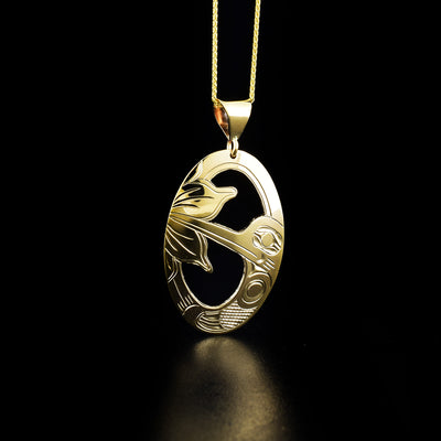 This 14k Gold Over Hummingbird Pendant is hand carved by Kwakwaka'wakw artist Harold Alfred. The design depicts a hummingbird feeding from a flower. The middle of the pendant is cut out. The pendant measures 1.5" x 0.81".