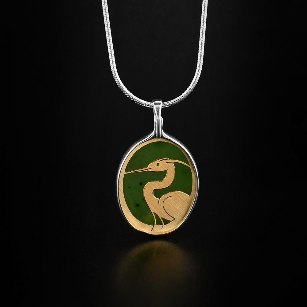 This jade pendant is made from sterling silver, 14K gold and A+ grade BC jade. There is a depiction of the Heron carved into a gold plate that is set on the jade giving the depiction gorgeous color.