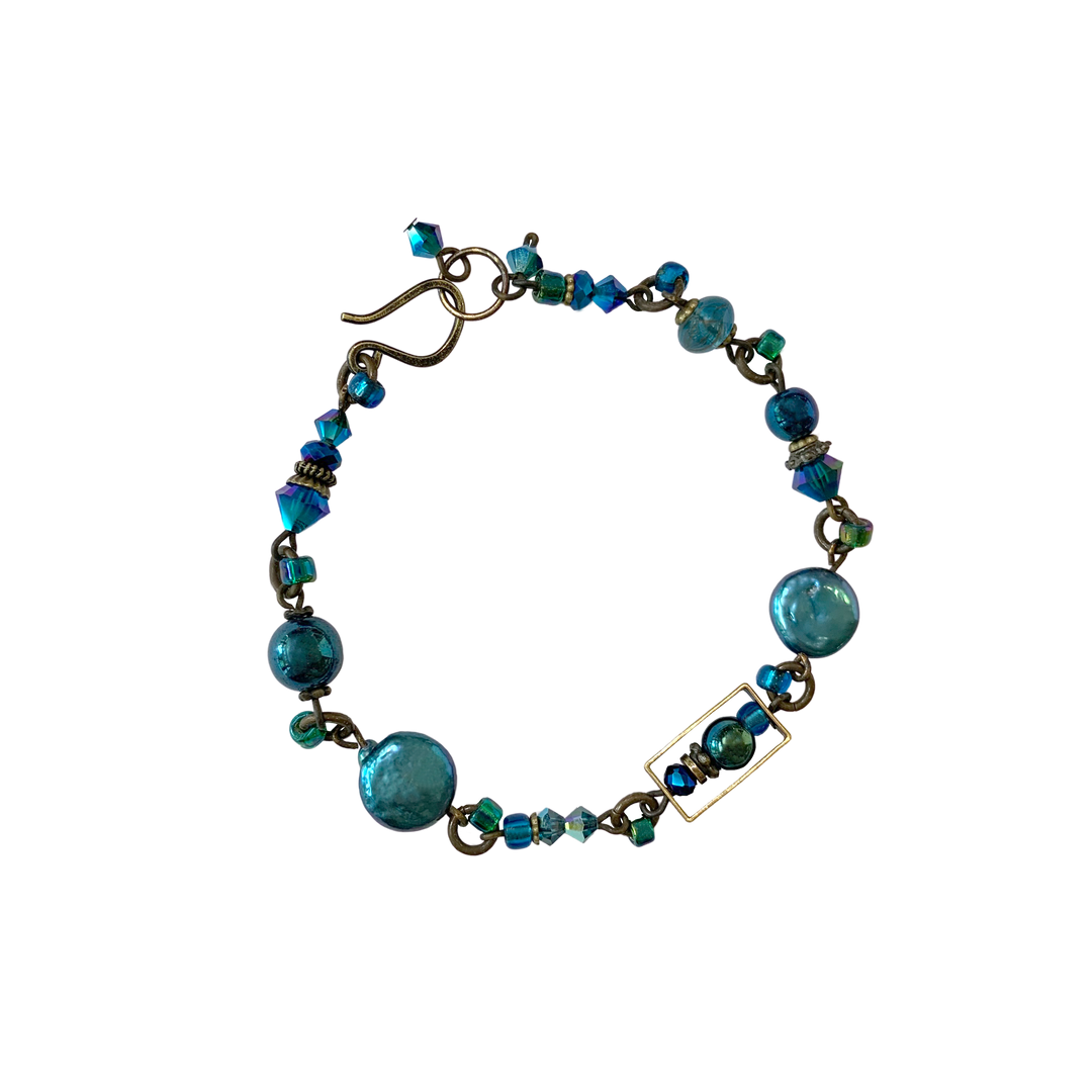 This blue crystal bead bracelet is made from brass, Swarovski crystal, freshwater pearls, and glass. The beads are different shapes and sizes and made from all of the listed materials.