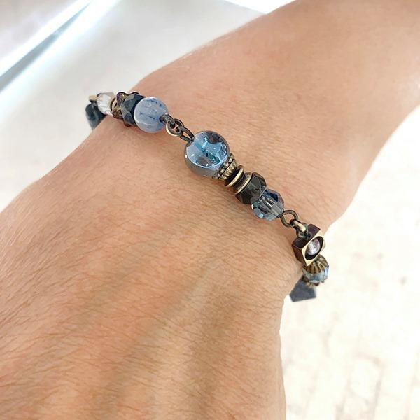 This blue crystal bracelet is made from  Austrian crystal, faceted glass, dumortierite, aventurine, apatite, kyanite and glass. The brass chain bracelet features beads of different shapes and materials.