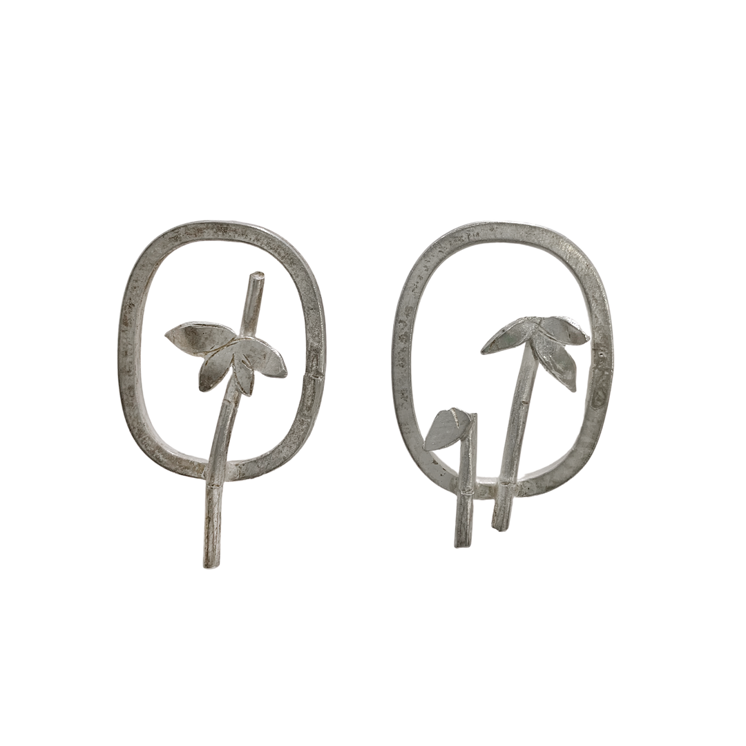These beach earrings are made from sterling silver and have a cutout design that depict palm trees on the beach. There is an oval frame around the trees.