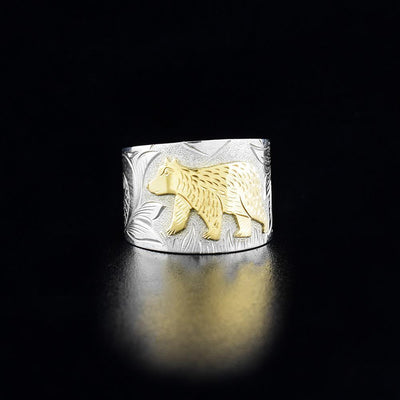 Side view of bear walking through wilderness. Hatch marks on bear to show fur. Bear is done in 10K gold, rest of ring is done in sterling silver. Size 5.