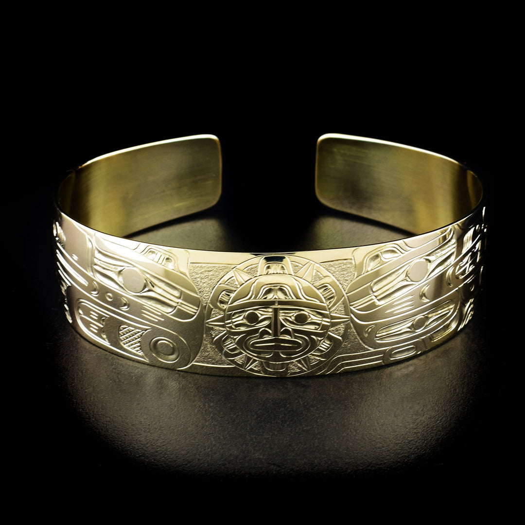 This 14K gold cuff bracelet has a single, wide band with a gap in the back. There are depictions of the Wolf, the Raven and the Sun carved into the band.