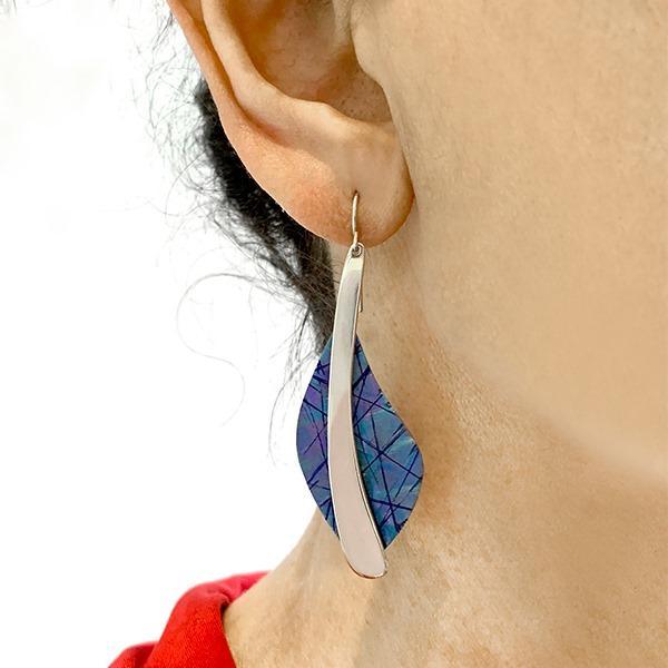 These dangling titanium earrings are made from sterling silver and anodized titanium with long feather shaped hangs. There is a silver piece in the middle with colorful, blue titanium hangs on either side.