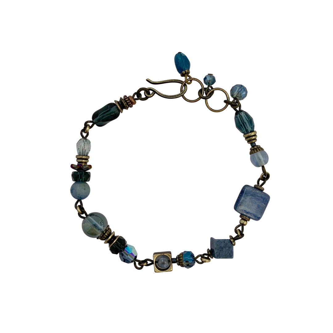 This blue crystal bracelet is made from  Austrian crystal, faceted glass, dumortierite, aventurine, apatite, kyanite and glass. The brass chain bracelet features beads of different shapes and materials.