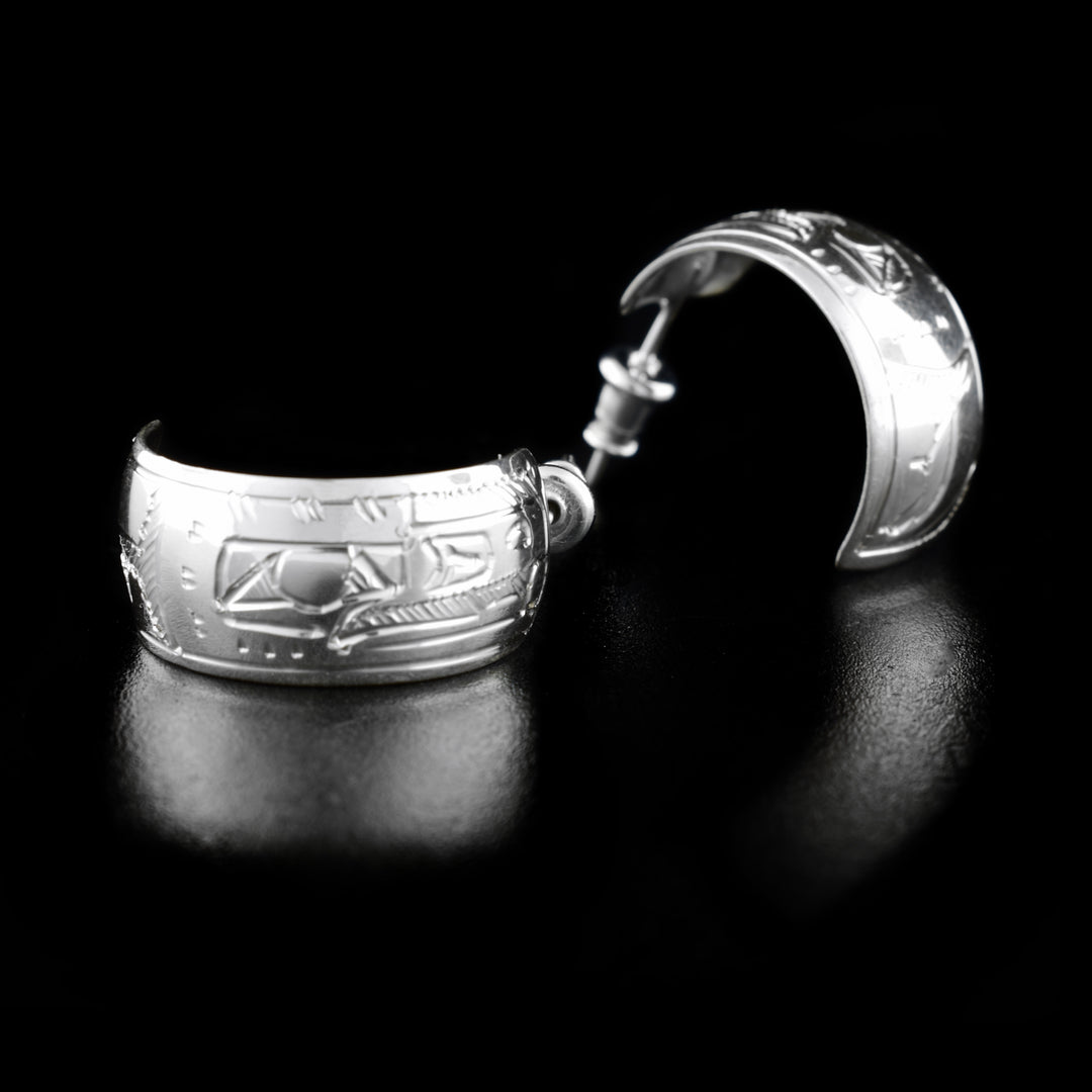 These wide hoop earrings are made form sterling silver and have wide bands curved into hoops with a gap in the back. There are depictions of the Raven carved into the surface of the band.