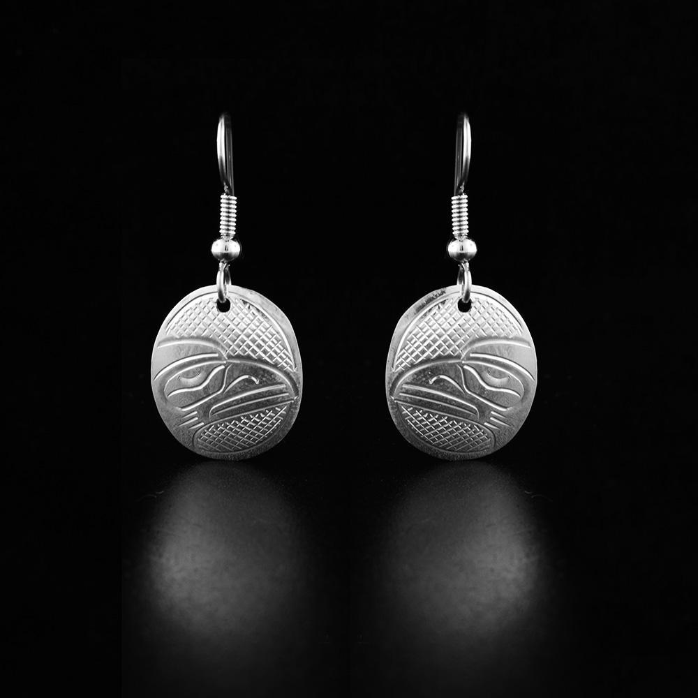 These sterling silver earrings have oval shaped hangs with depictions of the Raven carved into the surface of the hangs. 