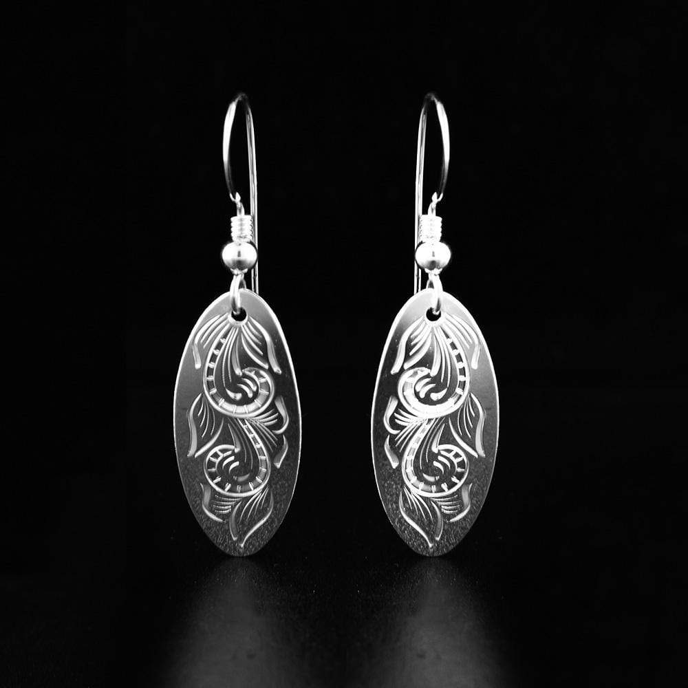 These flower earrings are made from sterling silver and have oval shaped hangs. There are floral designs that have been carved into the surface of the hangs.